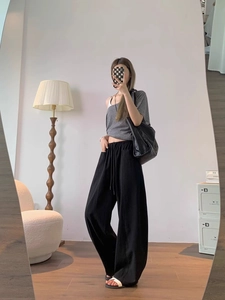 Detail of high-waist wide-leg trousers with elastic drawstring waistband and side pockets