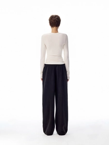 Rear view of model wearing a beige long sleeve slim fit top and black wide leg trousers
