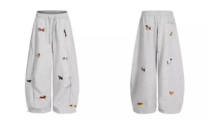 Close-up detail of light gray sweatpants featuring colorful dachshund dog embroidery patterns
