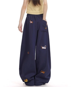 Detail of navy wide-leg sweatpants featuring embroidered dachshund patterns and drawstring hem