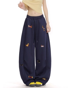 Detail shot of navy wide-leg sweatpants featuring colorful cartoon dog embroidery designs