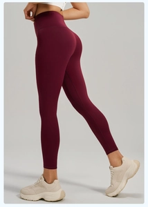Gros plan du legging de yoga bordeaux taille haute montrant l'effet galbant et le tissu mat