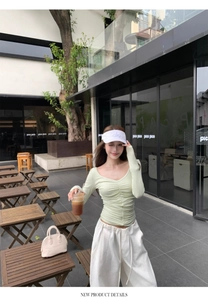 Outdoor shot of light green long sleeve ruched top paired with white wide leg trousers