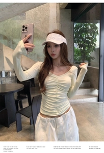 Detail view of the ruched V-neckline and slim-fit long sleeve top in soft light green