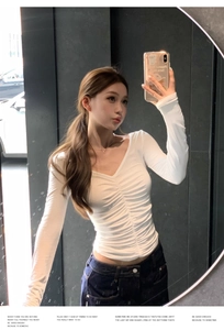 Detailed view of white V-neck long sleeve top with ruched front and slim fit design
