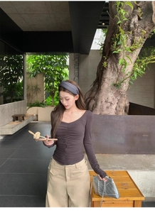 Detail of slim-fit ruched long sleeve t-shirt in dark brown with waist-shaping pleats