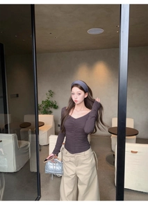 Close-up of ruched V-neckline on a slim-fit long sleeve t-shirt in dark coffee brown