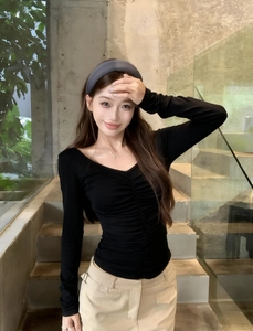 Close-up of ruched front detail and soft knit fabric on a black long sleeve V-neck top