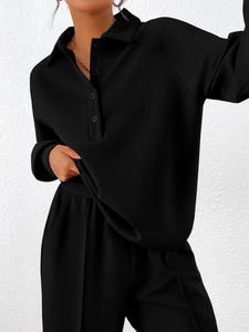 Close-up of black long-sleeved polo collar tracksuit with ribbed cuffs and side pockets