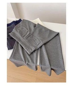 Dettaglio dei pantaloni grigi a vita alta a gamba larga con tasche a patta decorative