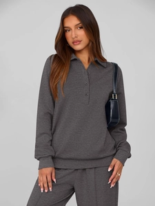 Detail view of dark grey knitted set fabric with three-button collar and ribbed texture