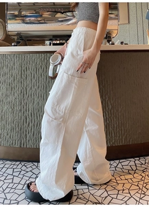 Détail de la taille haute élastique et des poches cargo sur le pantalon blanc à jambes larges