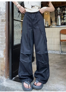 Détail d'un pantalon cargo noir à jambes larges avec cordons longs et poches latérales chic