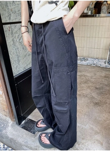 Détail du pantalon cargo noir à jambes larges avec grandes poches et taille à cordon
