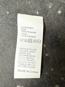 Detail of the 100% polyester material wash care label on a waterproof hooded rain jacket