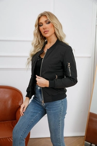 Detail of black women's bomber jacket with gold ring zippers and ribbed cuffs on sleeve