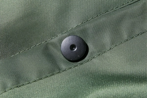 Detailed close-up of army green pilot jacket fabric with durable matte snap button
