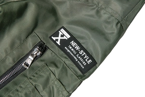 Close-up of military green MA1 bomber jacket with metal zipper and tactical arm patch detail