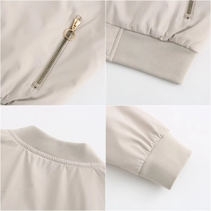 Detail view of beige bomber jacket featuring ribbed collar, cuffs and gold zipper pockets