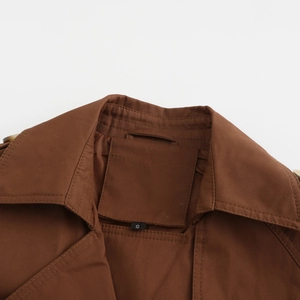 Détail du col à revers et étiquette de taille S sur trench en coton marron avec coutures