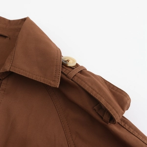 Détails du revers de trench-coat marron et des boutons marbrés sur les épaulettes