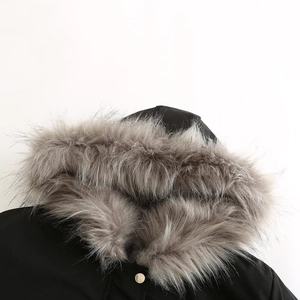 Detail of a black parka coat featuring a dense grey faux fur collar and gold metal snap button