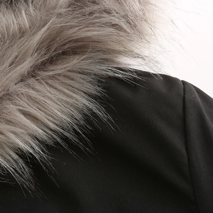 Detail of a black parka coat featuring a dense, fluffy grey faux fur collar trim