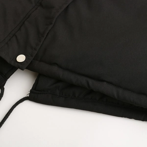 Detail of black parka jacket showing silver metal button, drawstring and quilted fabric