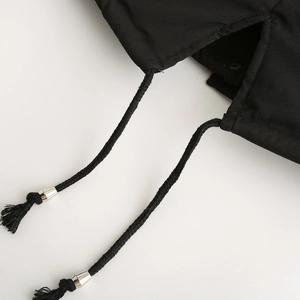Close-up of black parka drawstrings with silver metal toggles and snap button detail