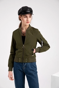 Gros plan de la manche du blouson aviateur vert armée avec ruban décoratif noir