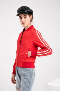 Detail of red bomber jacket featuring white sleeve stripes and ribbed baseball collar