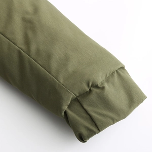 Gros plan du poignet élastique coupe-vent et du tissu texturé d'une parka vert olive