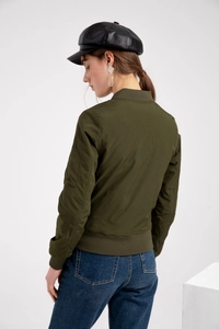 Détail d'un blouson aviateur vert foncé avec poignets côtelés et poche zippée sur la manche