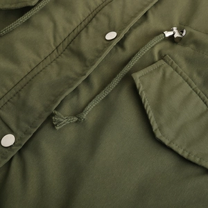 Détails d'une parka vert armée montrant les boutons métalliques et le rabat de la poche