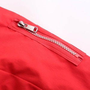 Détail macro de la fermeture éclair en métal argenté sur le tissu d'une parka rouge