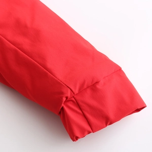 Détail de la manche d'une parka rouge montrant le poignet élastique et le tissu lisse