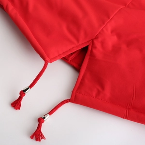 Détail de l'ourlet de la parka rouge avec cordons de serrage tressés et embouts en métal