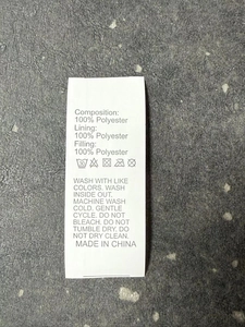 Close-up of garment care label showing 100% polyester material and washing instructions