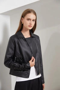 Détail d'une veste en similicuir noir avec lacets ajourés aux manches et à la taille