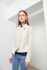 Close-up of silver metal studs on the shoulder of a cream-colored faux leather jacket