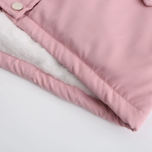 Détail d'une parka rose avec doublure chaude en fausse fourrure blanche et bouton-pression