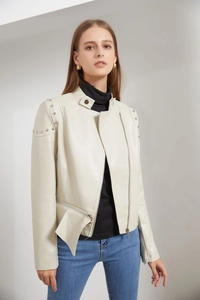 Detailed view of silver rounded studs on the shoulders of this cream faux leather jacket