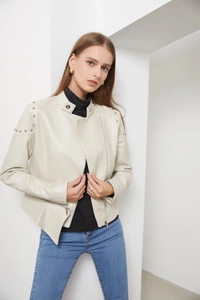 Detail of cream faux leather jacket with silver studs on shoulder and stand collar