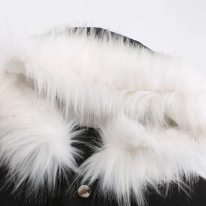 Détail du col en fourrure synthétique blanche et bouton argenté sur une parka noire