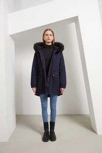 Detail of navy parka coat featuring an adjustable drawstring waist and faux fur hood