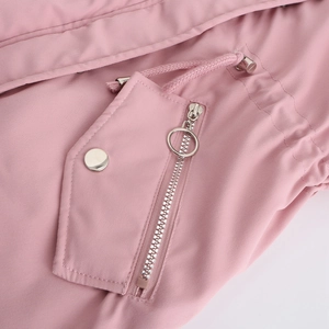 Détails d'une parka rose avec texture sergé, poches et fermetures éclair métalliques