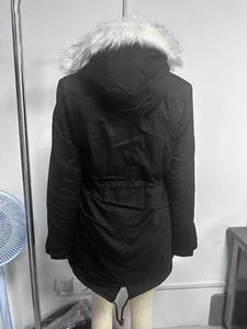 Détail de la parka noire montrant la bordure en fausse fourrure blanche et la taille ajustée