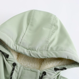 Détail de la parka vert clair avec doublure sherpa blanche et cordon de serrage de capuche