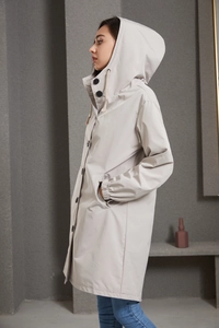 Detail view of water-resistant hooded trench coat with drawstring and black buttons