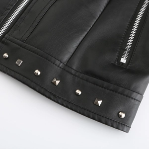 Detail einer schwarzen Kunstlederjacke mit silbernen Nieten und Metallreißverschluss